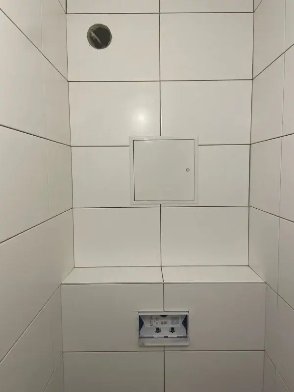 Wand-WC-Nische mit weißen Wandfliesen und Revisionsklappe