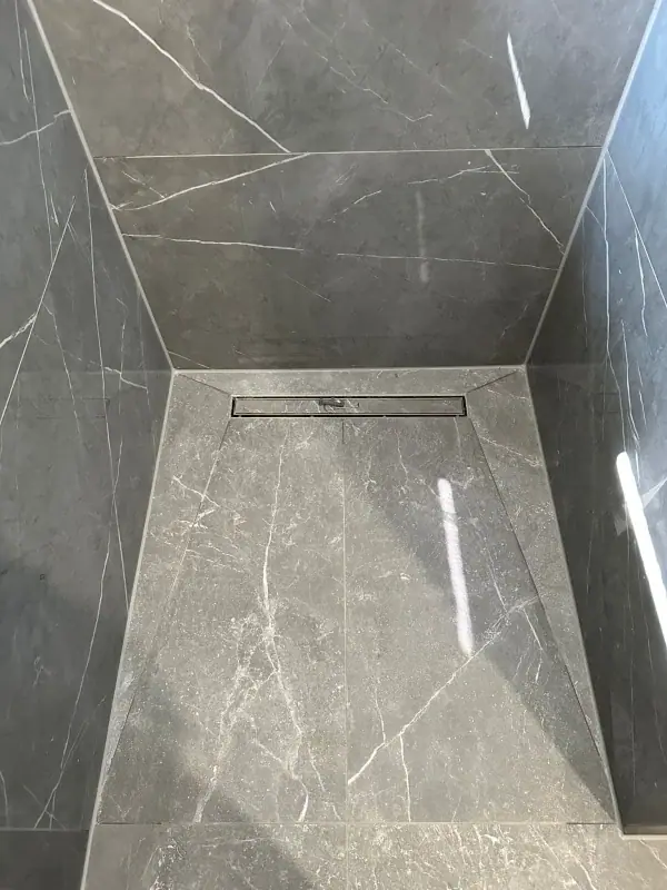 Bodengleiche Dusche mit Duschrinne und großformatigen Fliesen in Marmoroptik