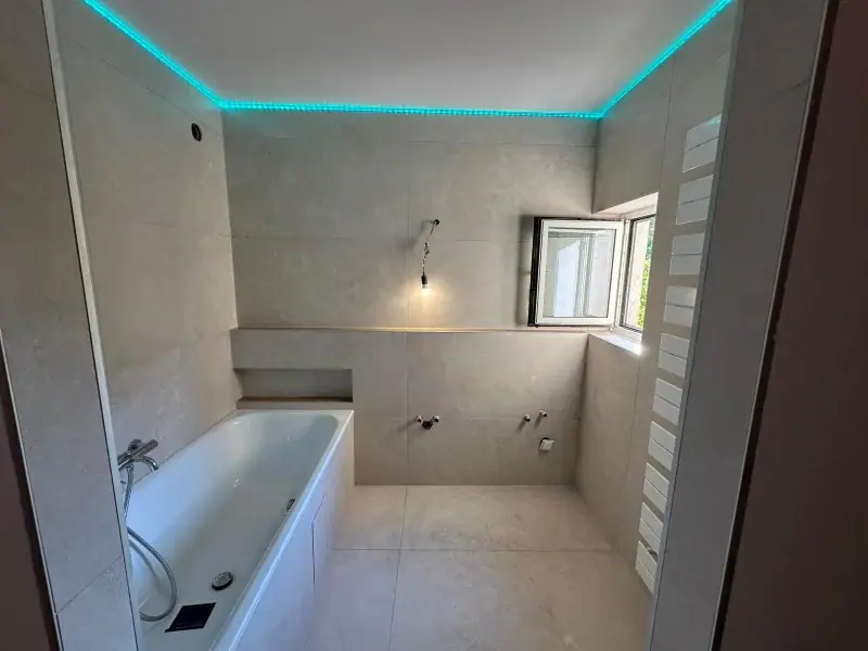 Badsanierung mit Badewanne, Ablagenische und großformatigen Wandfliesen in Beige