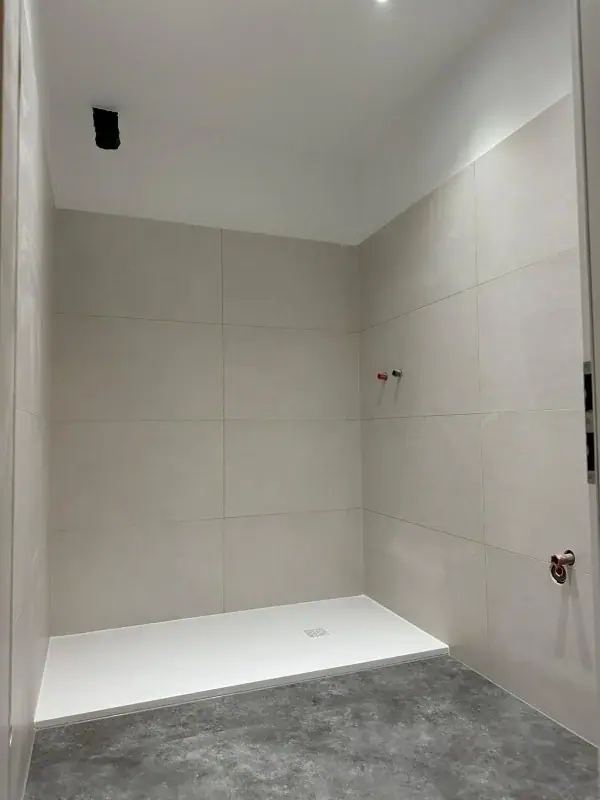 Dusche mit großformatigen hellen Wandfliesen vor dem Einbau der Armaturen