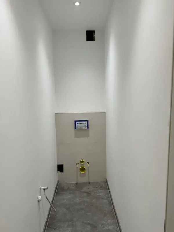 WC-Raum mit Vorwandinstallation und grauen Bodenfliesen