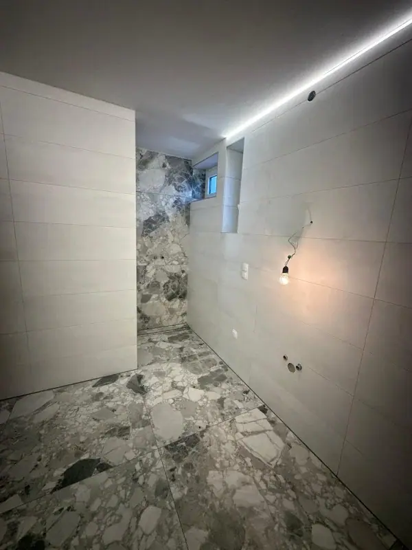Bad mit Bodenfliesen in Terrazzo- und Natursteinoptik und hellen Wandfliesen
