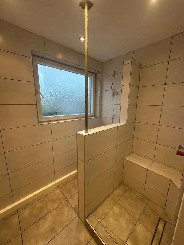 Begehbare Dusche mit gefliester Sitzbank, Trennwand und Bodenrinne