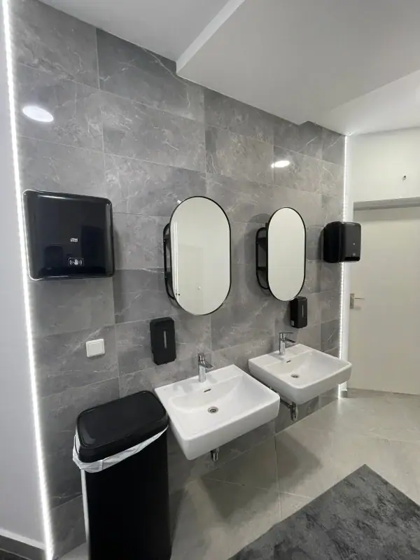 Sanitärraum mit grauen Wandfliesen in Steinoptik und zwei Waschbecken